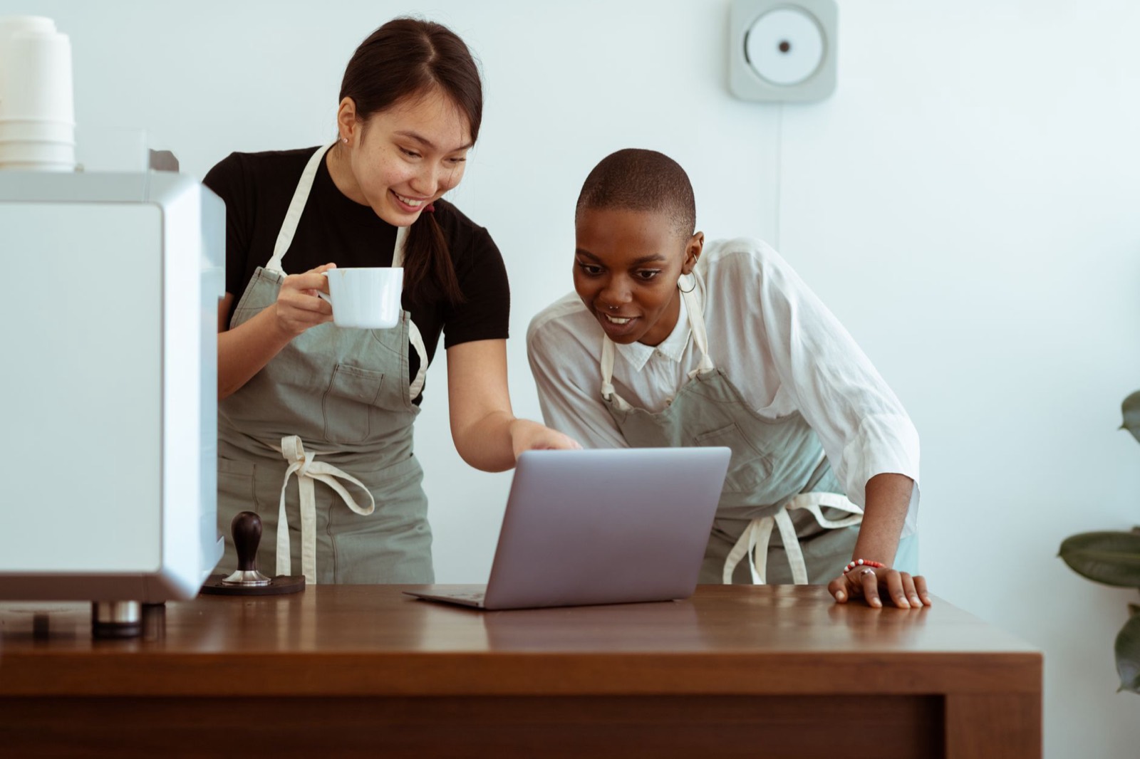 Two café staff checking hours together on a laptop