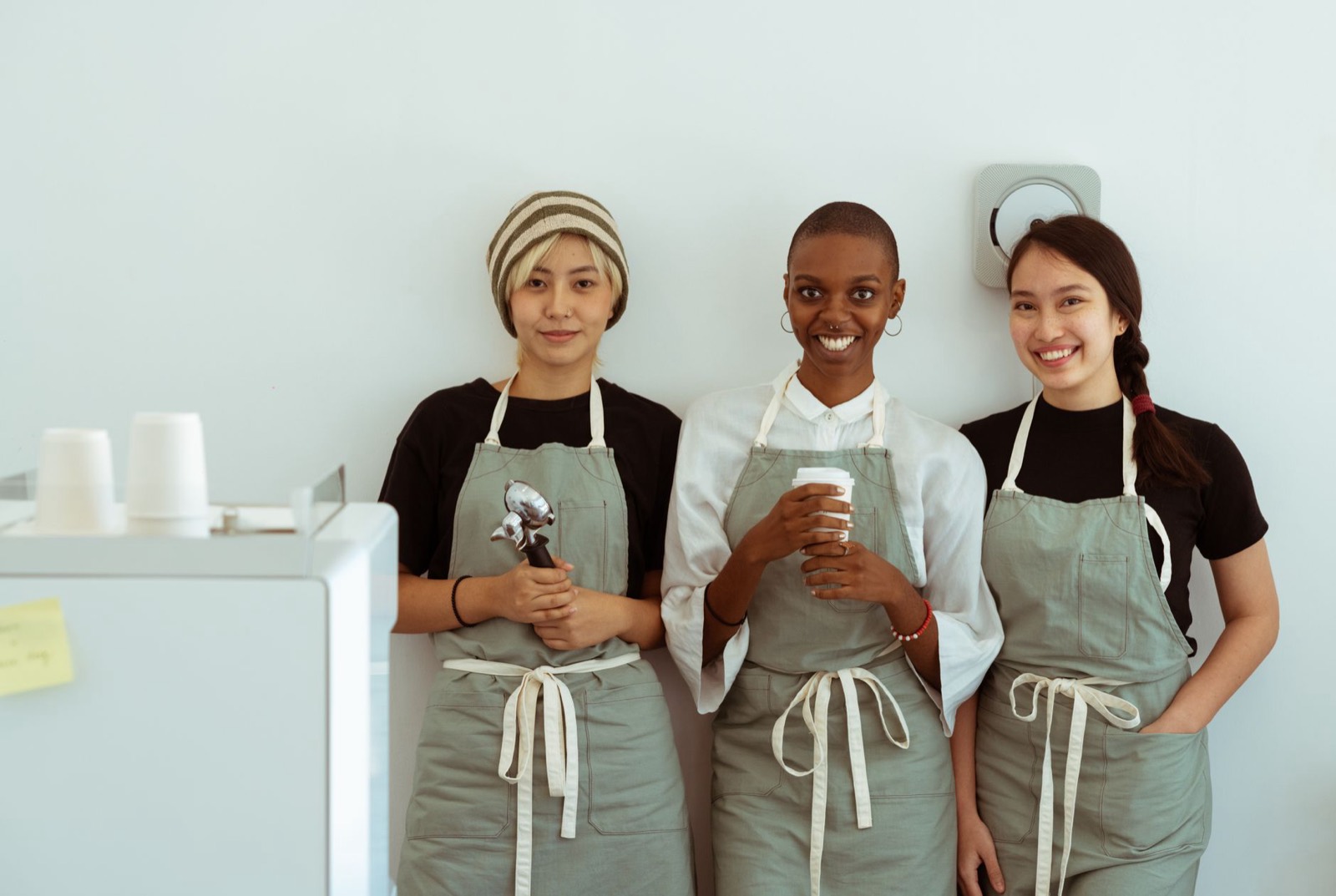 Three café team members in aprons standing together