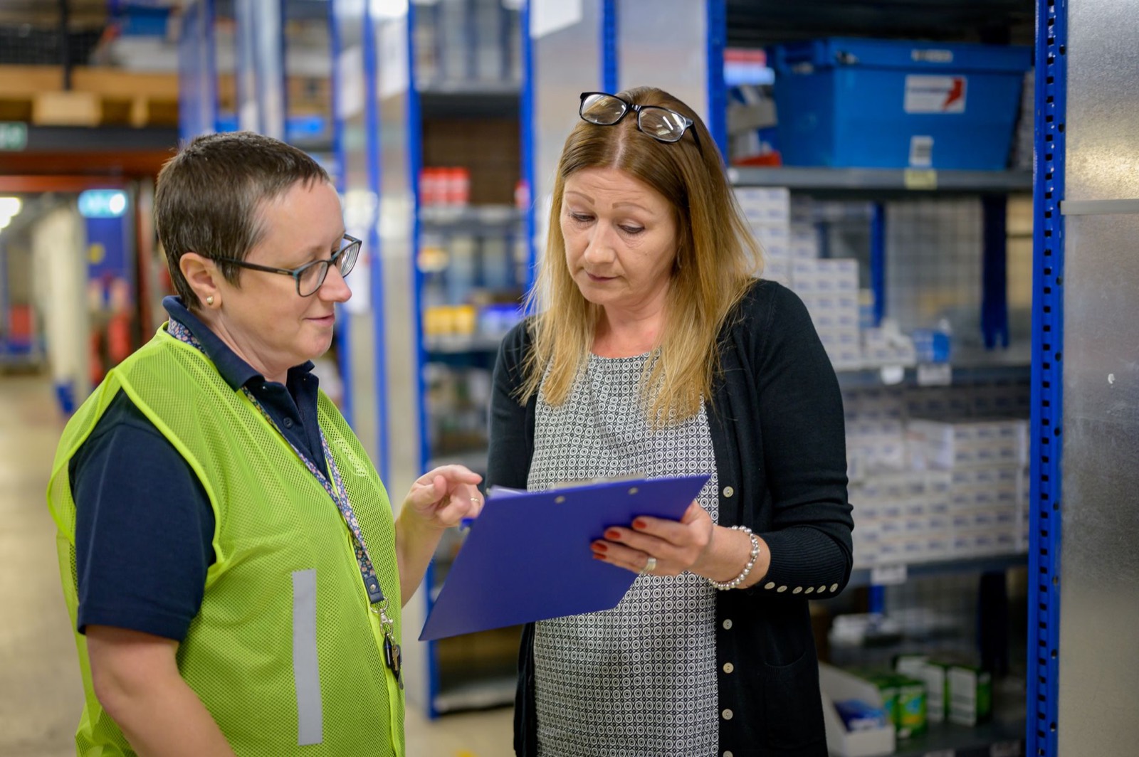 Warehouse supervisor and colleague reviewing a checklist on a clipboard